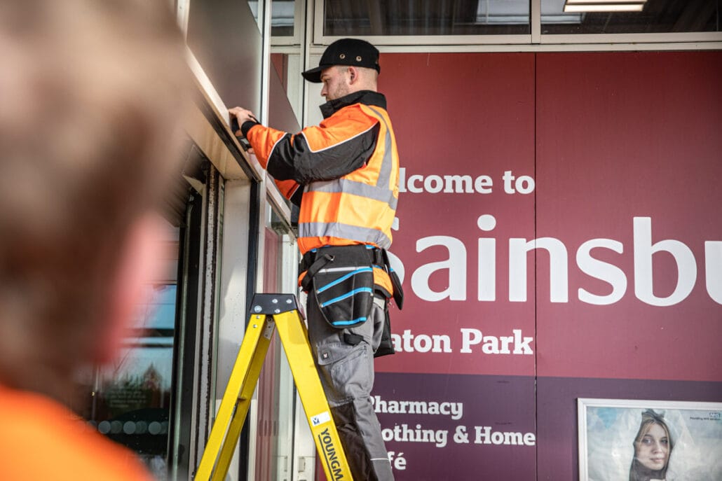 Commercial Photographer Manchester photo of men fixing door at sainsburys